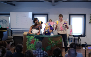 Middle school students performing a puppet show on stage during Lott Music Studio summer camp.
