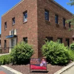 The exterior of the Lott Music Studio building in downtown Ames, featuring a promotional poster for our summer music camp.