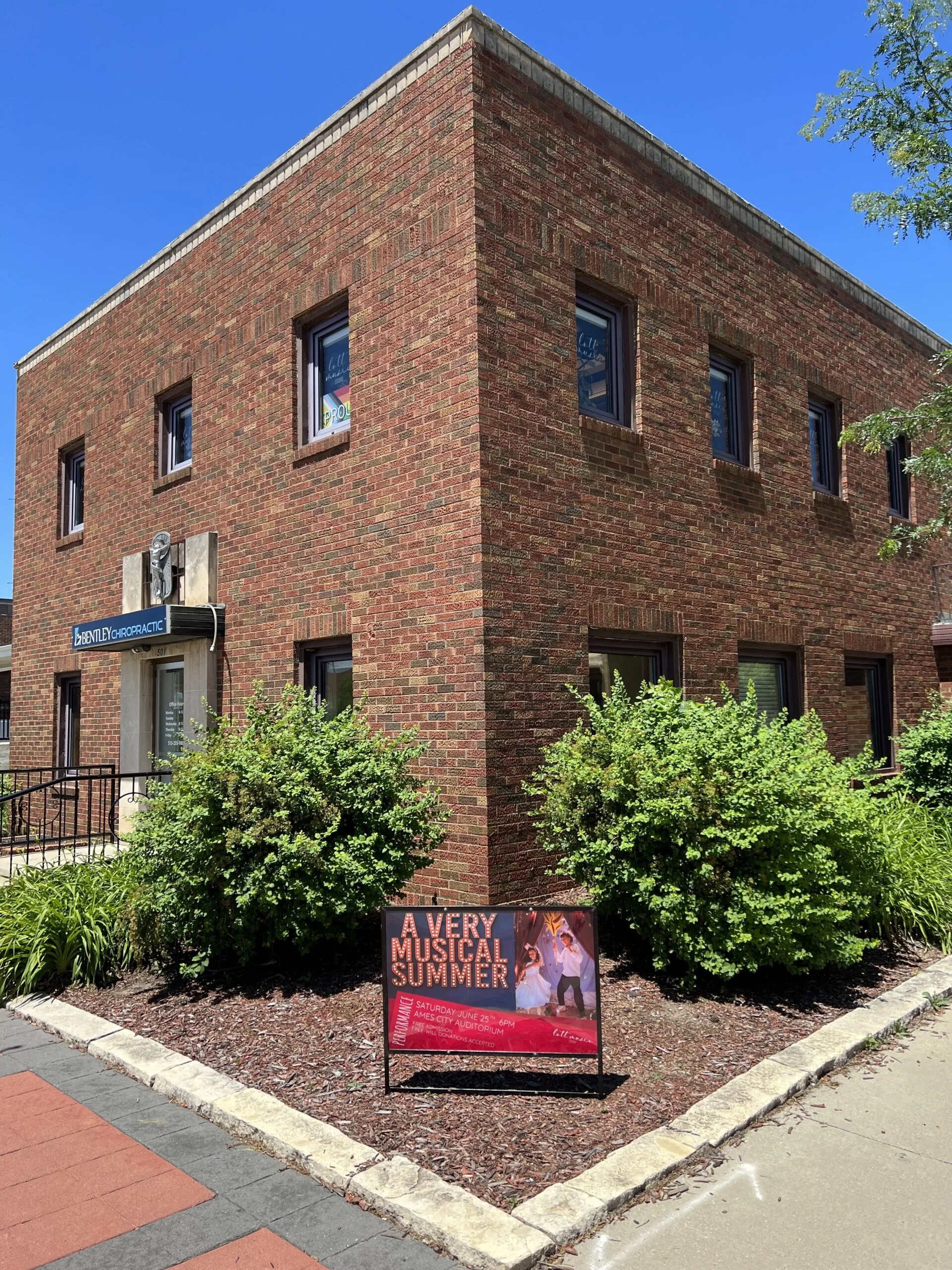 The exterior of the Lott Music Studio building in downtown Ames, featuring a promotional poster for our summer music camp.